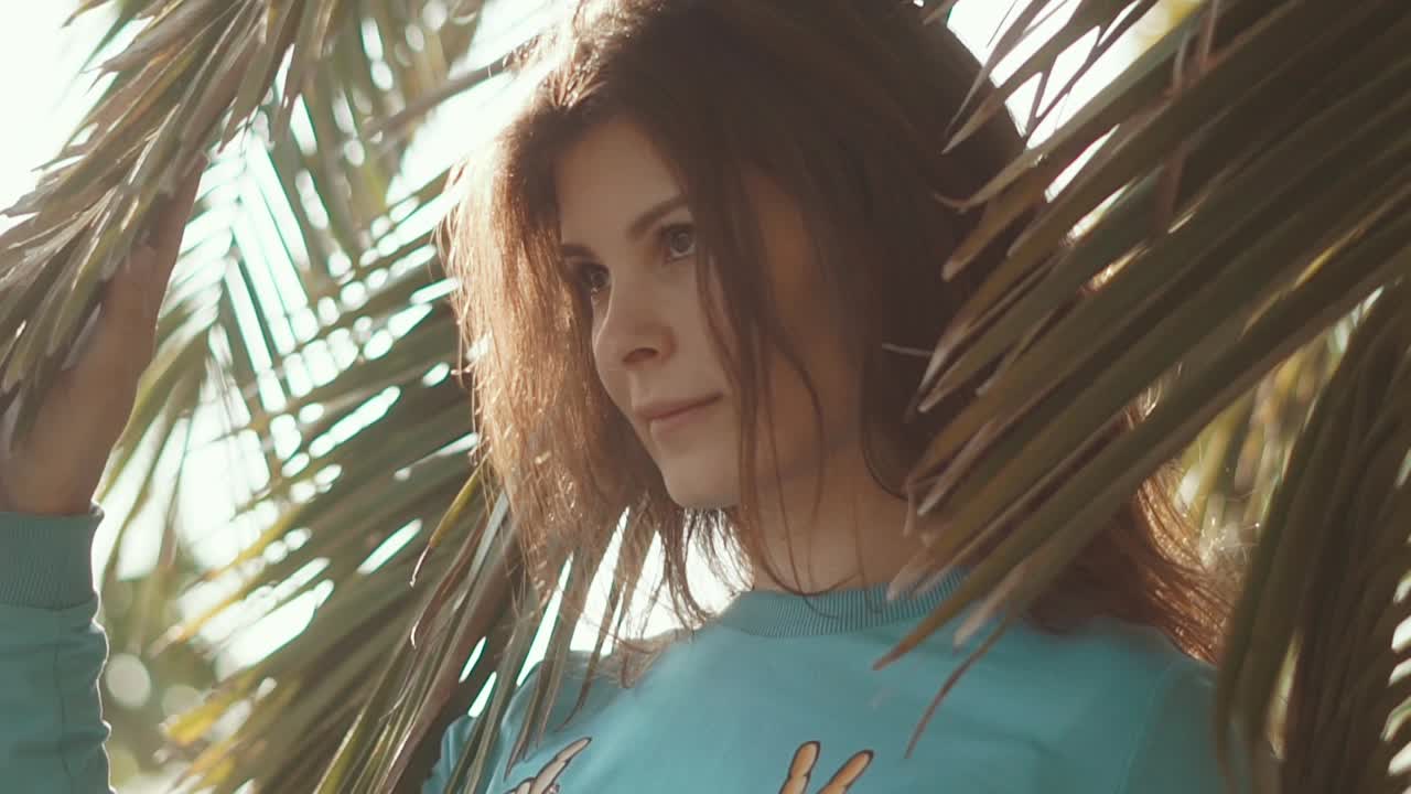 mujer con un suéter azulado entre las palmeras