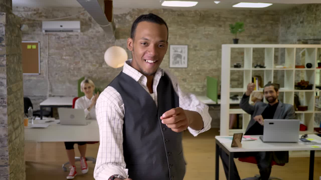 jovem empresário africano está dançando no escritório, colegas estão aplaudindo, conceito de trabalho, conceito de relaxamento