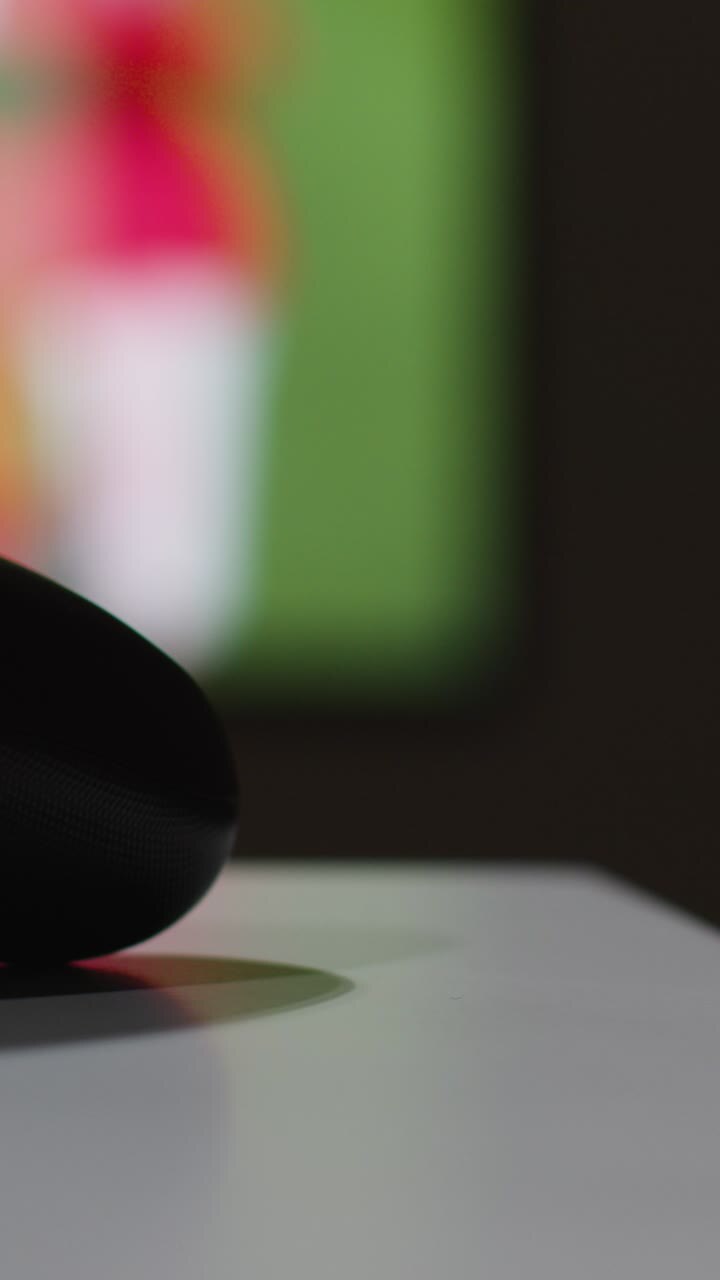 Video verticale, primo piano macro di un controller di videogioco con sfondo schermo di gioco sportivo