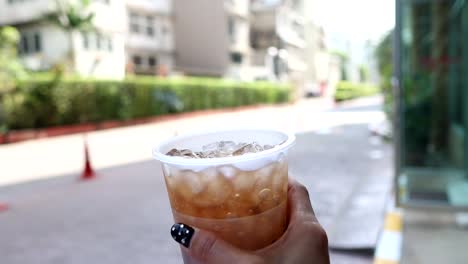 hand stirring a cup of iced coffee.