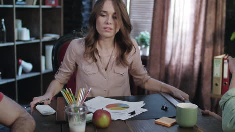 Business-woman-sitting-at-erratic-table-during-office-meeting-with-coworkers