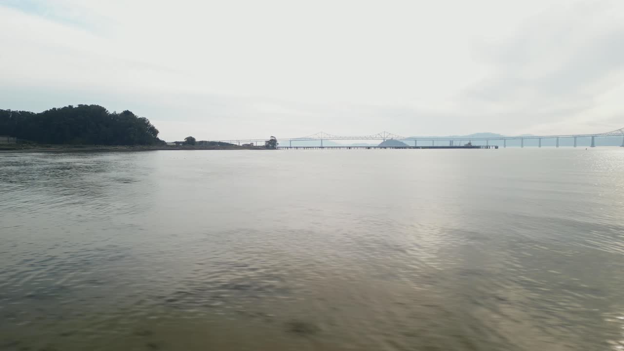 Aerial low tracking pan right above waters, Richmond Bridge from Point Molate Beach Richmond California USA