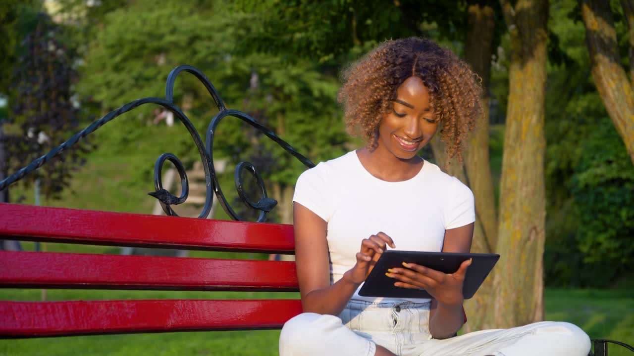 Young african american woman using tablet in university park