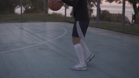 Rückseitenaufnahmen-Einer-Jungen-Basketballspielerin,-Die-Mit-Einem-Ball-Auf-Dem-Außenplatz-Joggt-Und-Ihn-In-Den-Korb-Wirft