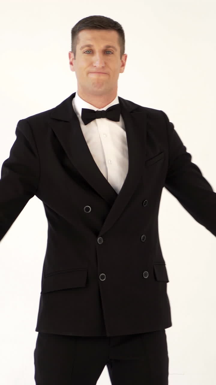 fun man is coming with his raised hands and whirling with a smile on his face on a white background Vertical video