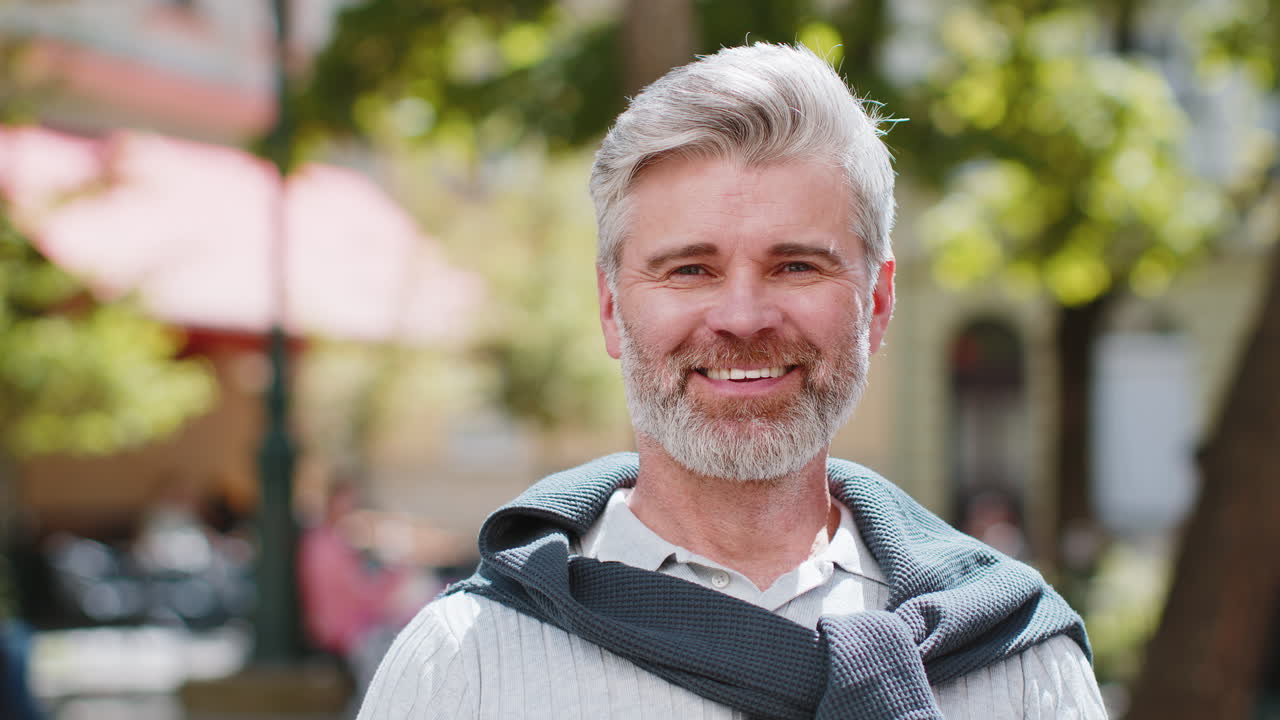 Portrett av glad skjeggete voksen mann som smiler vennlig, med et fornøyd uttrykk og ser avslappet inn i kameraet.