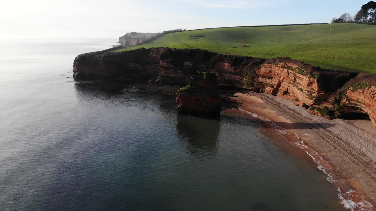 drone aéreo vuela hacia abajo de las majestuosas y cristalinas aguas en la línea de costa en ladram bay