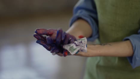 Woman-artist-wipes-hands-from-paint-watercolor