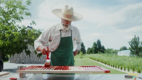 hombre mayor pintando persianas de madera al aire libre