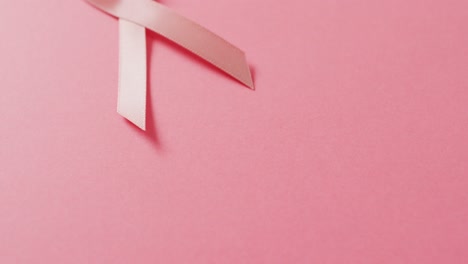 video of pink breast cancer ribbon on pale pink background