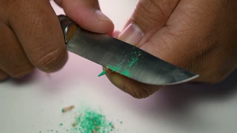 Footage-of-hands-slowly-sharpening-a-pencil-and-some-coloured-pencils-with-a-sharp-knife