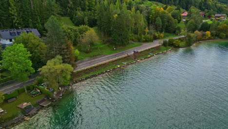 Coastal-road-near-lake-adorned-with-trees-against-a-backdrop-mountains