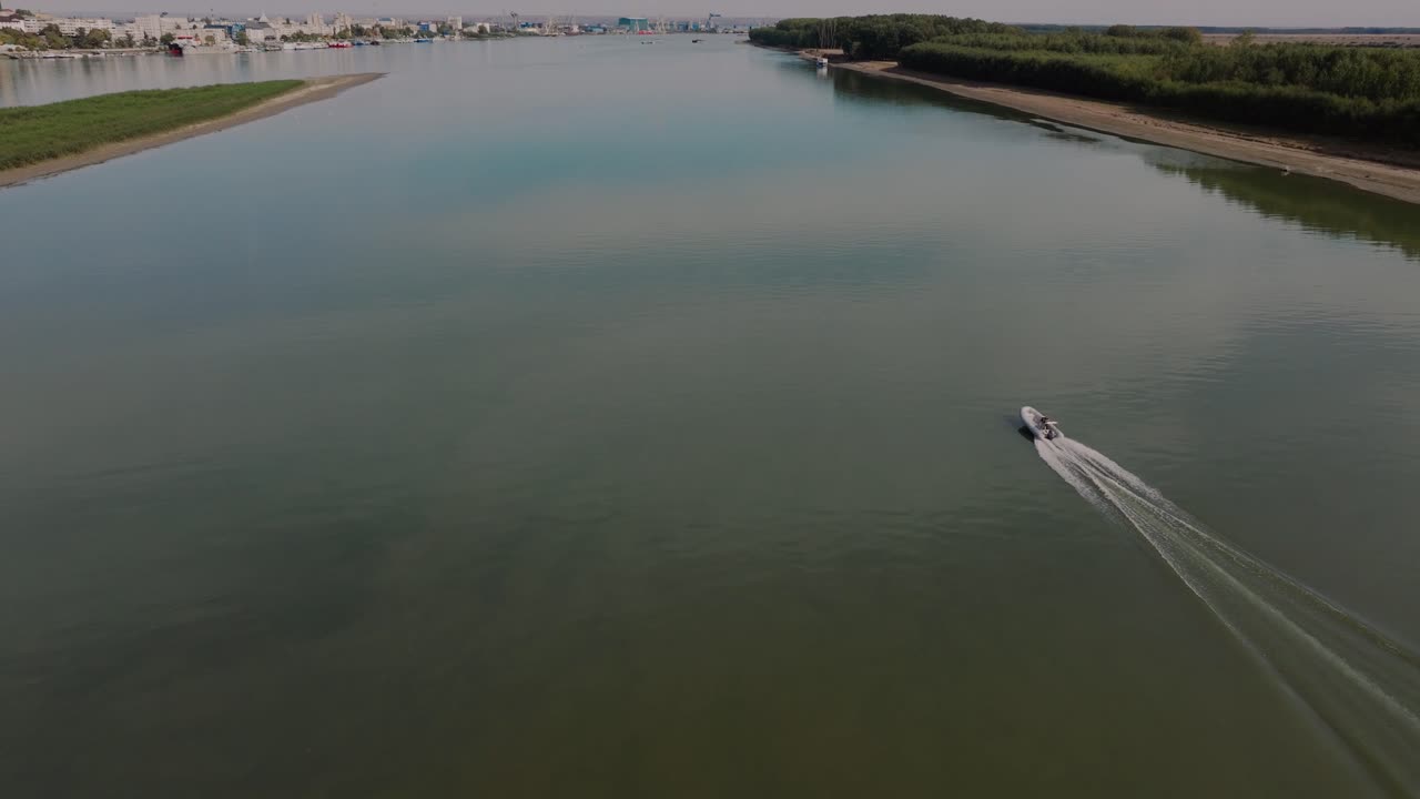 одинокий человек плывет на небольшой надувной лодке вдоль большой спокойной реки