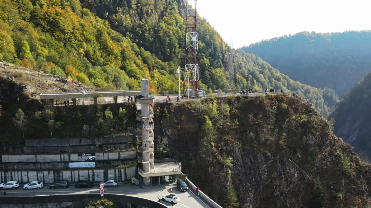 Aerial drone view of nature in Romania. Valley in Carpathian mountains with viewpoint full of people near the Vidraru dam, slopes with lush forest