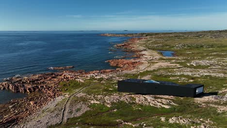 largo estudio de arquitectura moderna a lo largo del sendero de joe batt en la isla de fogo desde un drone orbital aéreo, terranova, canadá