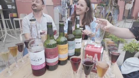 three glasses of different porto wines on a wooden table with bottles in the background