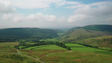 aerial shot over the english lake district with farm land and mountains, bright sunny day