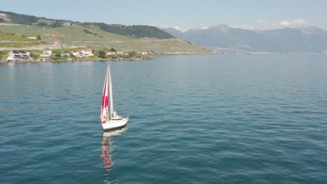 aerial orbit of small sail boat on a vast, blue lake