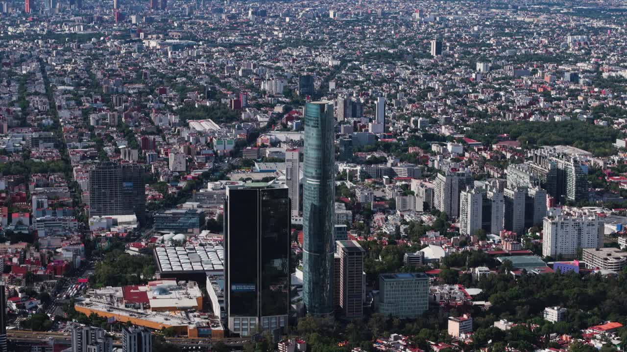 Aerial shot shows a skyscraper towering over Mexico City's south under a pristine, clear sky