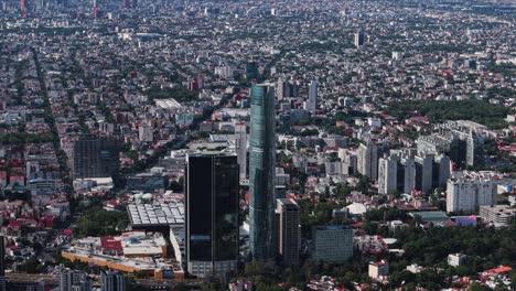 aerial shot shows a skyscraper towering over mexico city's south under a pristine, clear sky