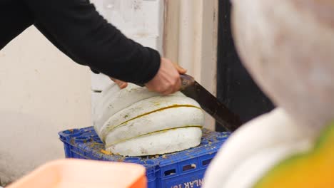 un hombre cortando una calabaza en un mercado