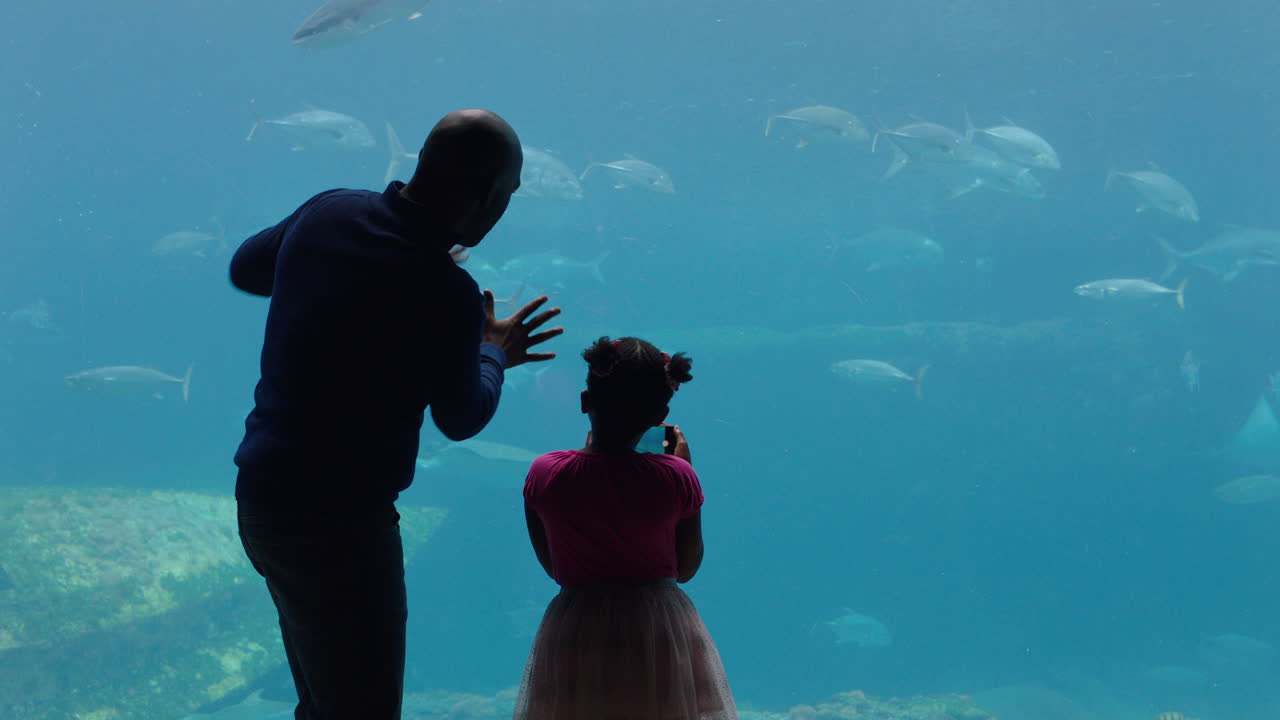 padre con su hija en el acuario mirando el tanque de peces enseñando a un niño curioso sobre la vida marina padre mostrando a su hija animales marinos en el oceanario