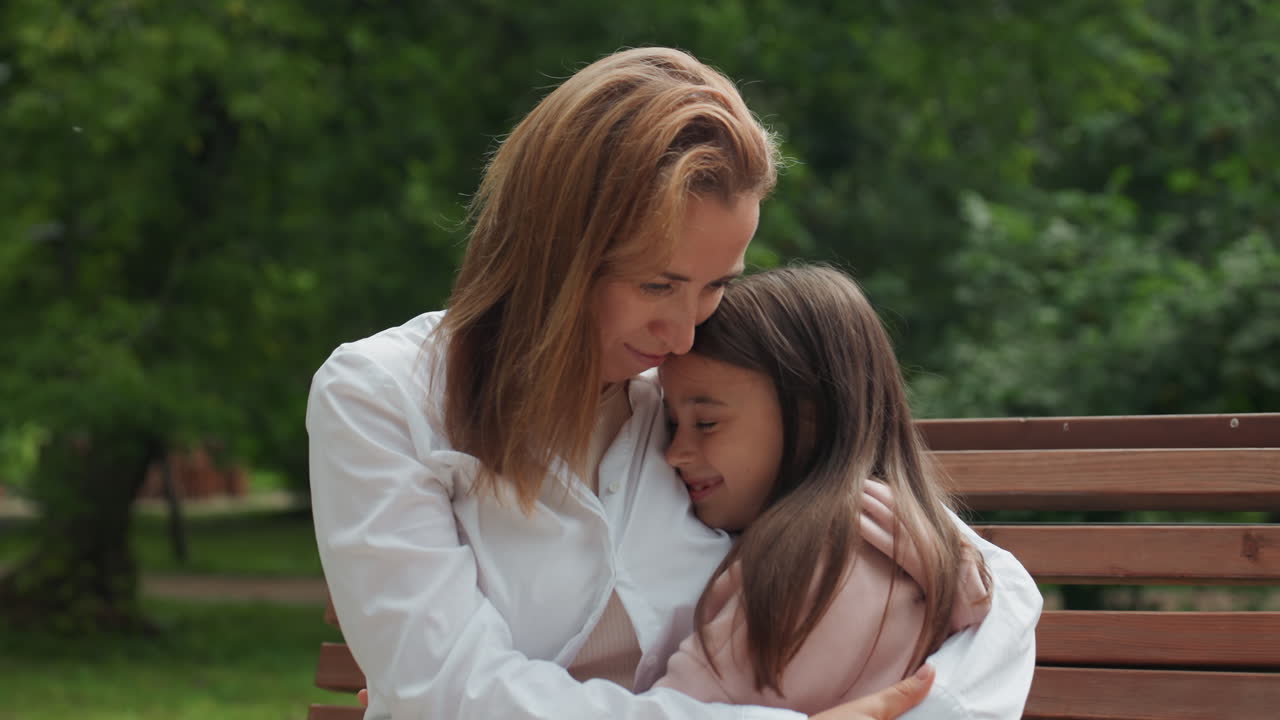 Mutter-Tochter-Umarmung. Die Mutter tröstet ihr Kind sanft. Eine ruhige Szene, in der die Mutter ihre Tochter friedlich umarmt. Die mütterliche Figur bietet Geborgenheit und Trost durch Berührung und sanfte Worte.