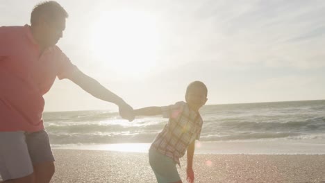 Glücklicher-Hispanischer-Großvater-Und-Enkel,-Die-Bei-Sonnenuntergang-Am-Strand-Laufen