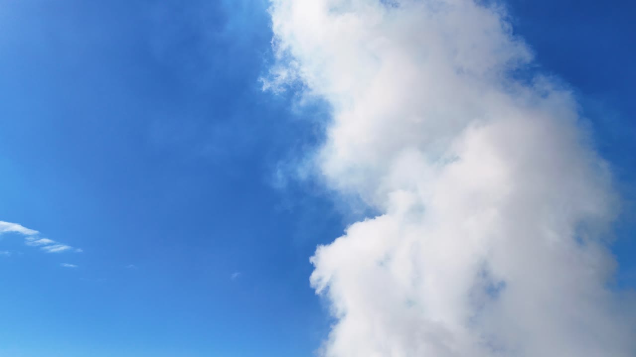 White clouds against a vibrant blue sky, highlighting air pollution and climate change themes. Bright lighting and static camera capture the scene