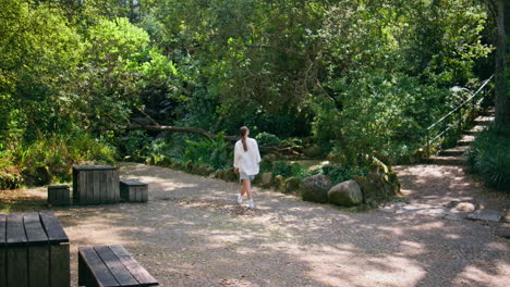 woman walking forest recreation place looking greenery. lady enjoying green park
