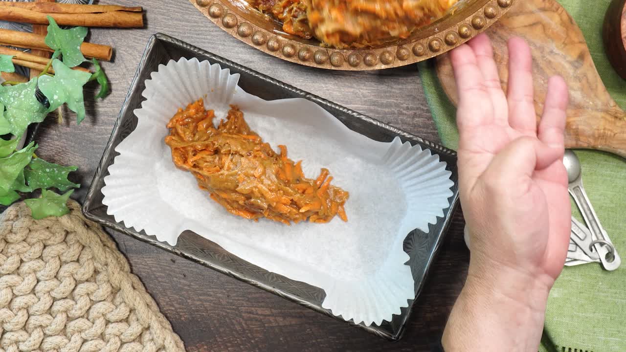 Baking a carrot cake loaf with cream cheese icing and topped with roasted salted pecans. Making a Autumn dessert with carrots, flour, sugar, nuts and frosting. Adding batter to a baking loaf pan.
