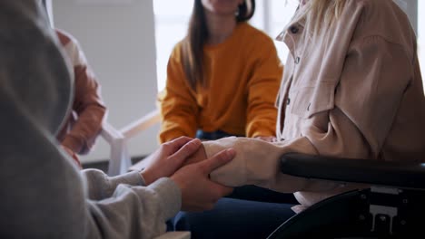 grupo de personas en una sesión de terapia, los miembros se toman de la mano.