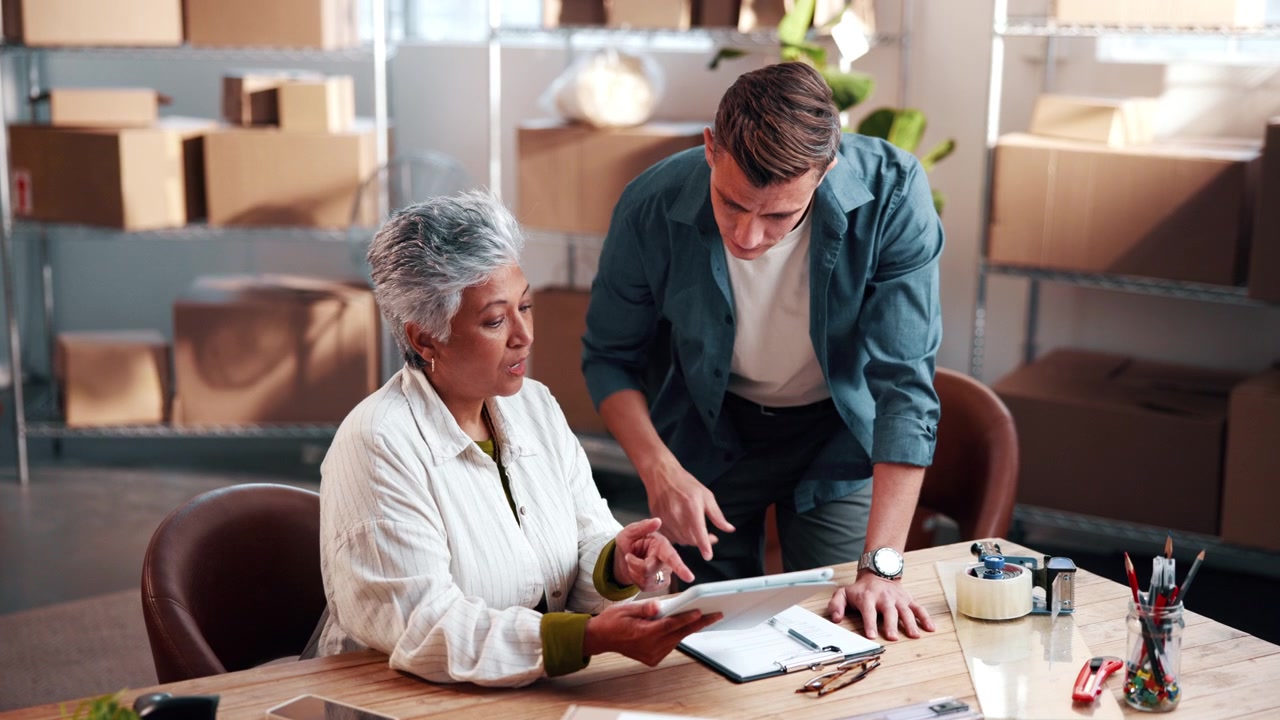 Business Colleagues Reviewing Data on Tablet in Warehouse Office