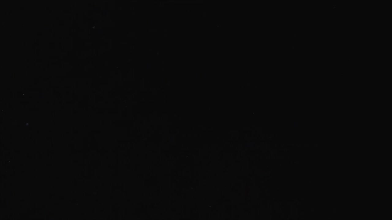 Colorful Glittering Particles Floating on Black Background