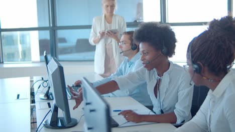 new call center operators in headsets working at computers