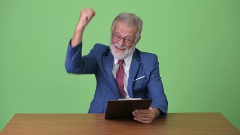handsome senior bearded businessman against green background