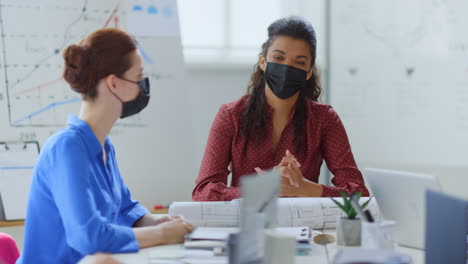 Maskierte-Menschen-Beim-Brainstorming-Im-Büro.-Geschütztes-Team,-Sitzender-Tisch,-Sitzungssaal.