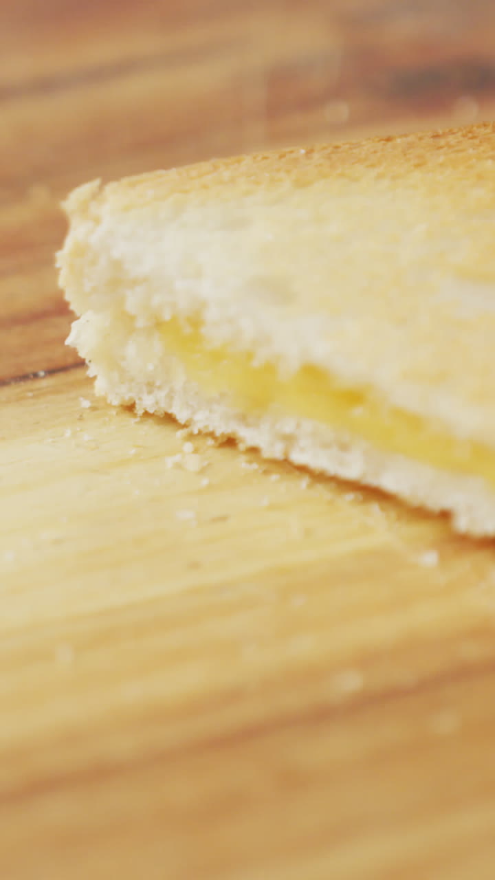 Video of slices of toasted cheese white bread sandwiches on wooden chopping board background