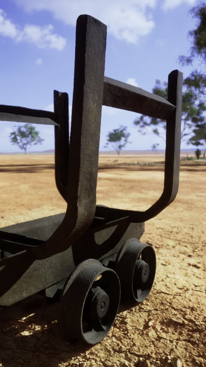 Unique rusty cart rests on dry landscape under vast sky during midday