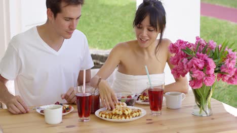 woman trying to feed annoyed man a waffle