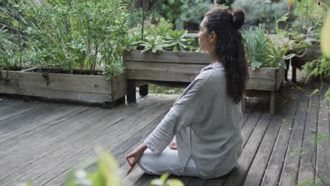 focused biracial woman practicing yoga meditation in sunny garden, slow motion with copy space