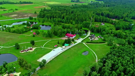 aerial drone zoom in shot over historic minhauzena manor in dunte, latvia surrounded green grasslands alongside small ponds along rural countryside at daytime