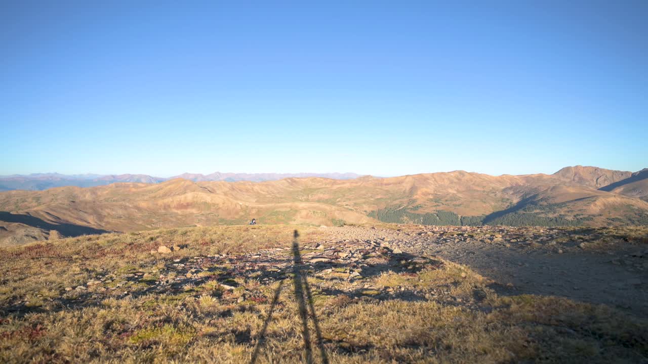 구름 없는 날 해가 뜨는 동안 산을 오르는 여성 하이커, 정적