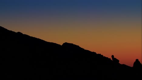 Breathtaking-sunset-lifestyle-traveler-surfer-shirtless-silhouette-dressing-himself-up-rocks-cliff-at-Cascais-Sintra-beach-medium-shot