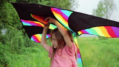 close-up view of a little girl holding a kite and looking at the camera in the park on a sunny day