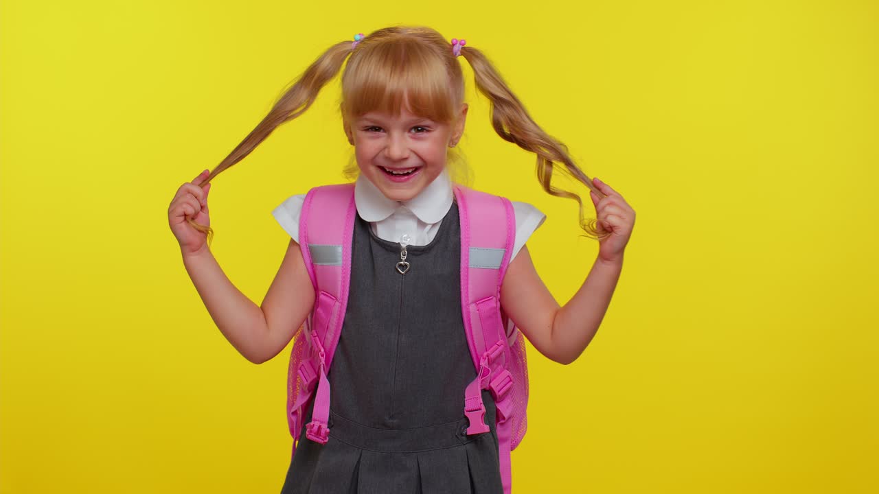 niña feliz niño en uniforme de escuela jugar con colas de caballo reírte tonto haciendo una cara tonta lúdica