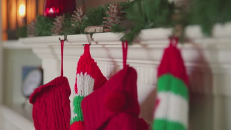 four christmas stockings hang on the decorated mantle