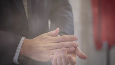 digital composite video of spots of light against mid section of man using hand sanitizer at office