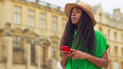 female tourist on vacation in oxford uk exploring city walking along broad street using mobile phone for directions and information 1