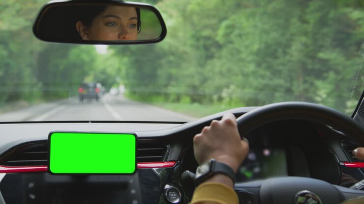 Primo piano di una donna autista con dispositivo vivavoce per telefono cellulare con schermo verde montato sul cruscotto